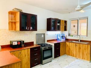 a kitchen with wooden cabinets and a stove top oven at Lux Suites 3 Bedroom Hydro Apartments Nyali in Mombasa