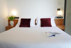 una camera da letto con un letto bianco e un libro sopra di Hotel Sunset a Rimini