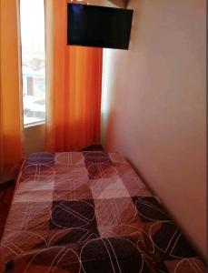 1 dormitorio con 1 cama y TV en la pared en Hospedaje Sumita Wasi, en Puno