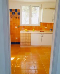 cocina con suelo de baldosa naranja y ventana en Il Giardino di Elettra, en Palmadula