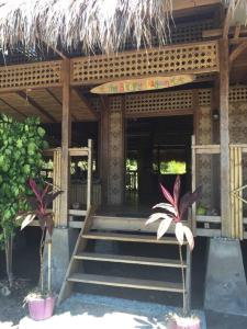 Hitokalak的住宿－The Sleepy Lagoon Beach House，一座带楼梯和稻草屋顶的建筑
