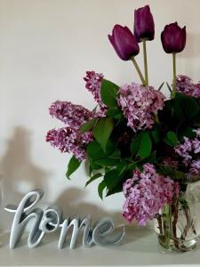a vase filled with purple flowers next to a word fame at B&B degli Allori in Moggiona
