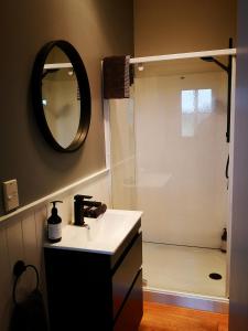 a bathroom with a sink and a shower with a mirror at Hilltop Haven in Tinopai