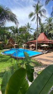 un complejo con una piscina con palmeras en el fondo en Villa Lova Sambirenteng, en Gretek