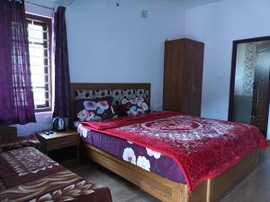 a bedroom with a large bed with a red bedspread at Karpagam Residency in Ooty
