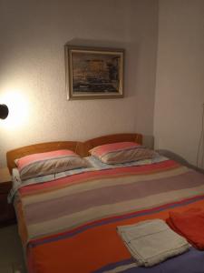 a bed in a bedroom with a painting on the wall at Apartman i Sobe Čule Cres in Cres
