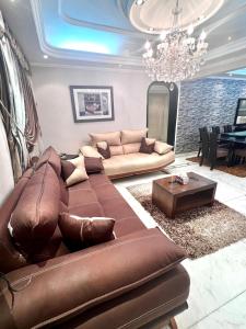 sala de estar con sofá marrón y lámpara de araña en شقة فندقية بانوراما علي النيل, en El Cairo