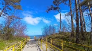 a path to the beach with a yellow fence at Domki Letniskowe Sarbilove in Sarbinowo