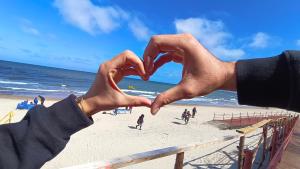 dos personas haciendo un corazón con sus manos en la playa en Domki Letniskowe Sarbilove en Sarbinowo
