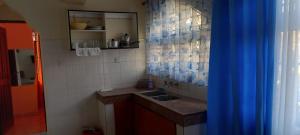 a small kitchen with a sink and a blue curtain at Lux suites Startup Apartments in Mombasa +9 photos