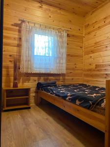 a bedroom with a bed and a window in a log cabin at Domek letniskowy nr 1 Przewięź in Augustów