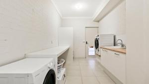 a white laundry room with a sink and a washing machine at Mazza by the Sea in Lake Tyers