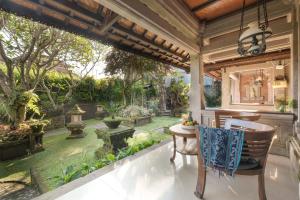 an outdoor patio with a table and chairs and a garden at Artini 2 Cottage Ubud in Ubud