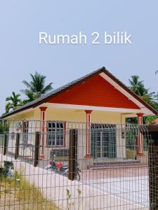 a house with a red roof and a fence at Adilah Homestay B in Pasir Puteh