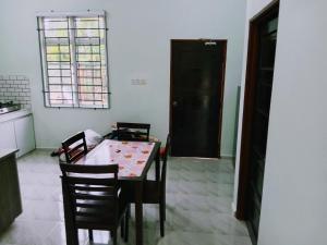 a dining room with a table and chairs and a window at Homestay Adilah B in Pasir Puteh