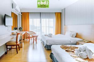 a hotel room with two beds and a desk at CBD 2 Hotel in Surat Thani