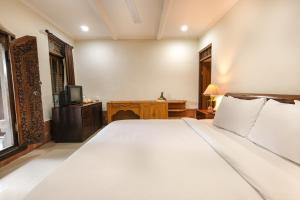 a bedroom with a large white bed and a television at Artini 2 Cottage Ubud in Ubud