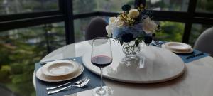 una mesa con una copa de vino y un jarrón de flores en Execlusive Suite 209 by Forest Khaoyai en Ban Huai Sok Noi
