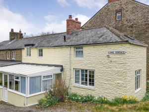 una antigua casa de piedra con un salón acristalado delante de ella en Daffodils en Coanwood