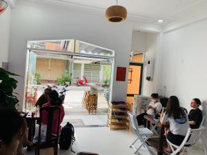 un grupo de personas sentadas en mesas en una habitación en Dom Hostel and Bar, en Hoi An