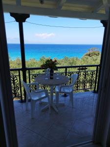 una mesa y sillas en un balcón con vistas al océano en VILLA AGIA AIKATERINI en Amoudi