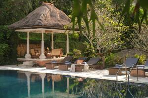 a swimming pool with a gazebo and chairs next to a swimming pool at Artini 2 Cottage Ubud in Ubud