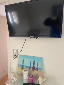 a television hanging on a wall with a picture of surfboards at Maison du bonheur in Saint-Mards-de-Fresne