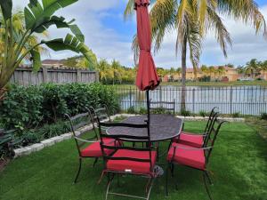 a table with four chairs and an umbrella at My Florida Lake House in Homestead