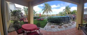 a man is standing on a patio with a pool at My Florida Lake House in Homestead