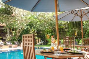 a table with food and an umbrella next to a pool at Artini 2 Cottage Ubud in Ubud