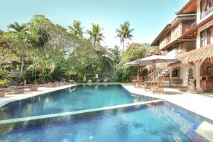 a pool with chairs and umbrellas next to a building at Artini 2 Cottage Ubud in Ubud