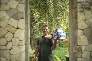 a man holding a tray with a cake on it at Artini 2 Cottage Ubud in Ubud