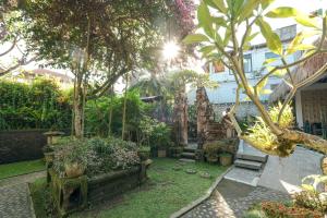 a garden with a bench and trees and a building at Artini 2 Cottage Ubud in Ubud