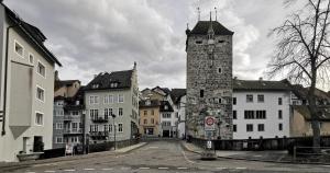 an old building with a clock tower on a street at Blick auf Schwarzen Turm - Freihofapartments in Brugg
