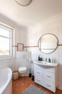 La salle de bains est pourvue d'un lavabo, de toilettes et d'un miroir. dans l'établissement Premium Apartment - Ausblick - Kamin - Balkon - Smart TV - Kaffeevollautomat, à Wernigerode