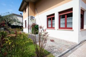 a white house with red windows and a garden at ABC Holiday in Salò
