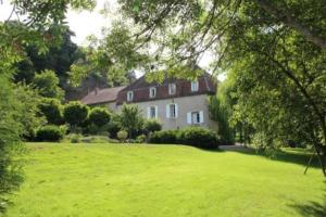 uma casa grande num campo com um quintal verde em L'annexe du Moulin Renaudiots em Autun