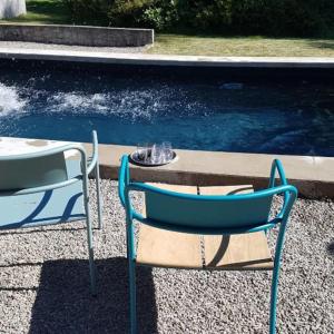 dos sillas azules sentadas junto a una piscina de agua en L'annexe du Moulin Renaudiots, en Autun