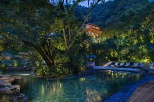 a pool in a garden with a house in the background at Bolian Resorts & SPA Chongqing in Chongqing