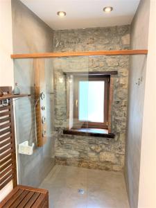 a glass shower in a bathroom with a stone wall at Alola Cimadevilla in Gijón