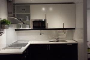 eine Küche mit weißen Schränken, einer Spüle und einer Mikrowelle in der Unterkunft Precioso apartamento junto a la ría in Limpias