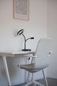 escritorio blanco con silla y lámpara en Modernes Apartment am Campus - Parken - Smart-TV - Kaffeevollautomat, en Wernigerode