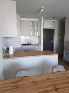 a kitchen with white cabinets and a wooden counter top at Apartament Wyłom 8 in Poznań