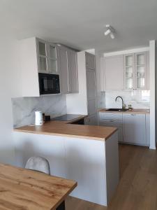 a kitchen with white cabinets and a wooden counter top at Apartament Wyłom 8 in Poznań