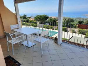 balcón con mesa, sillas y piscina en Casa Moro, en Trinità dʼAgultu