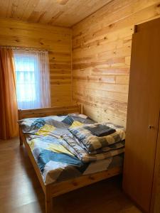 a bedroom with a bed in a wooden cabin at Domek letniskowy nr 1 Przewięź in Augustów