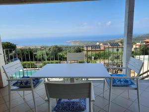 una mesa y sillas en un balcón con vistas al océano en Casa Moro, en Trinità dʼAgultu