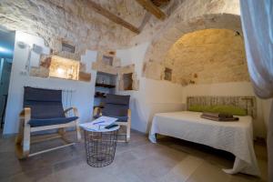 ein Schlafzimmer mit einem Bett, einem Stuhl und einem Tisch in der Unterkunft Trullo Terra di Alix Ex Terre di Santa in Ostuni