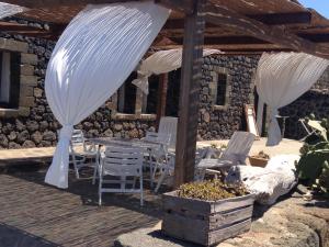 patio con tavolo e sedie sotto un padiglione di Pantelleria 4 passi dal mare a Pantelleria