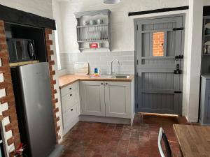 a kitchen with white cabinets and a gray door at Arundel Maltravers in Arundel